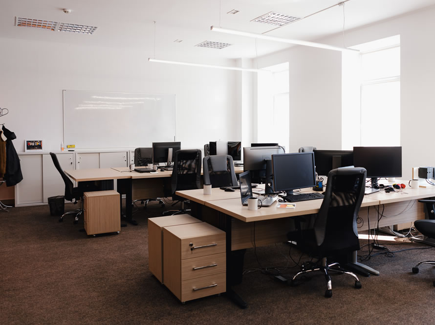 Oficina moderna y luminosa con estaciones de trabajo y una pizarra blanca en el fondo.